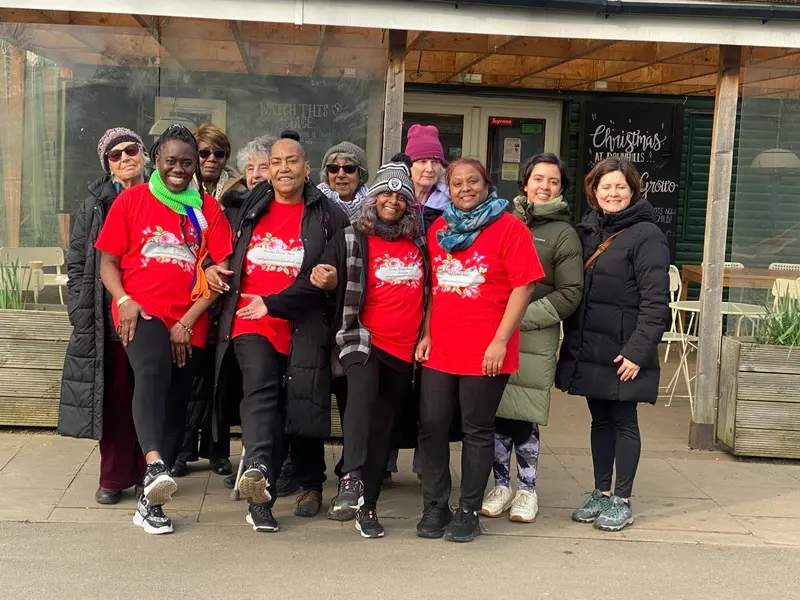 BADGE members in matching red T shirts with friends outside a park cafe